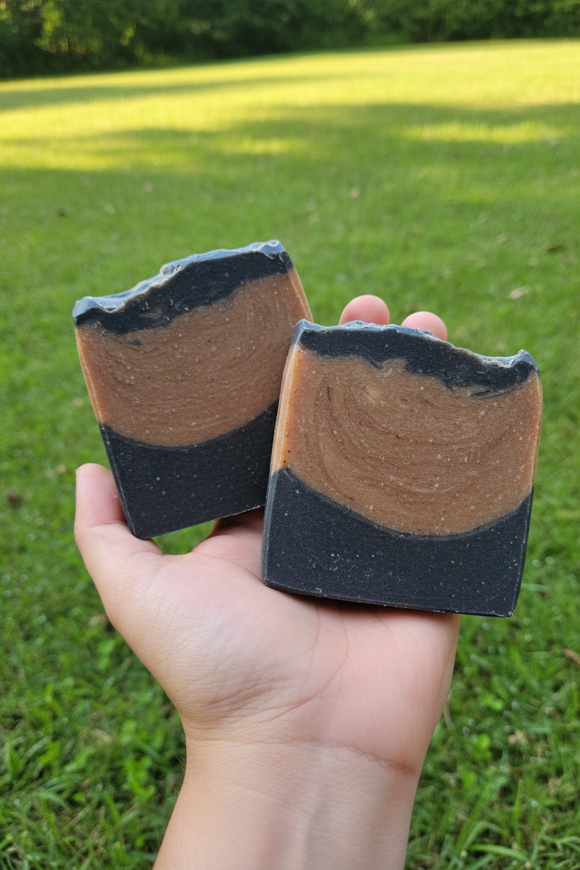 Hand holding two bar soapswith grass background
