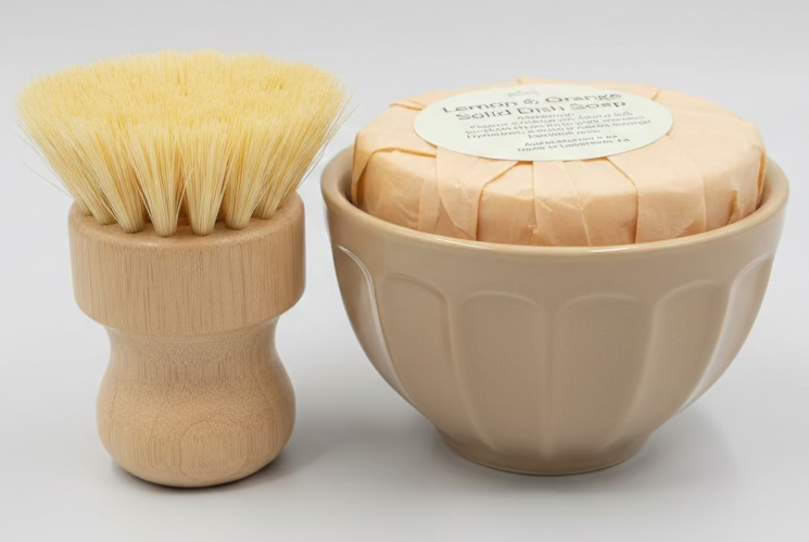 Set of brushes in a holder next to a loaf of bread on a tiled surface.