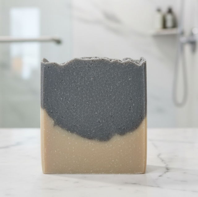 Hand holding a bar of soap with a marble background